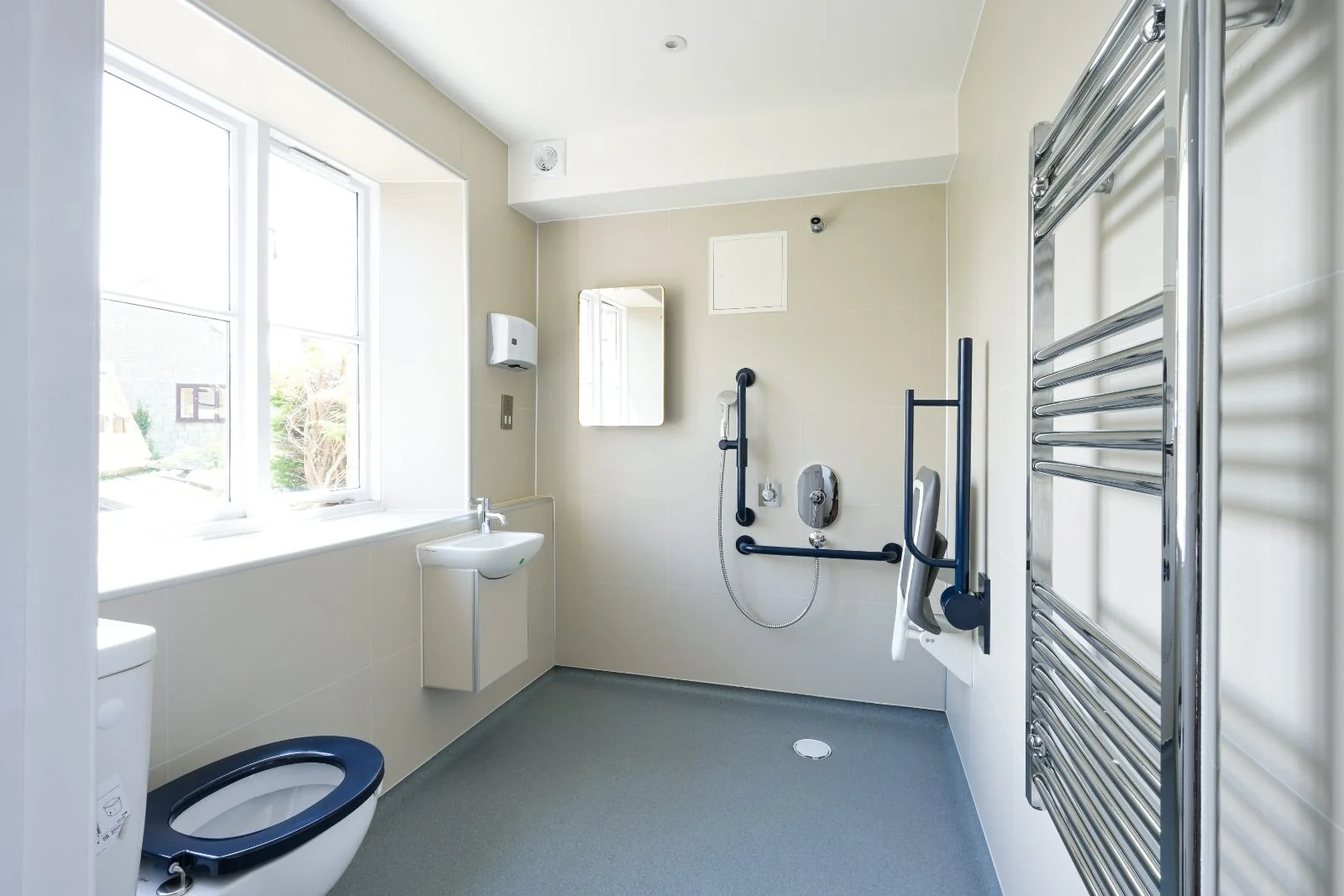 Level-access wet room with grab rails, shower seat and heated towel rail