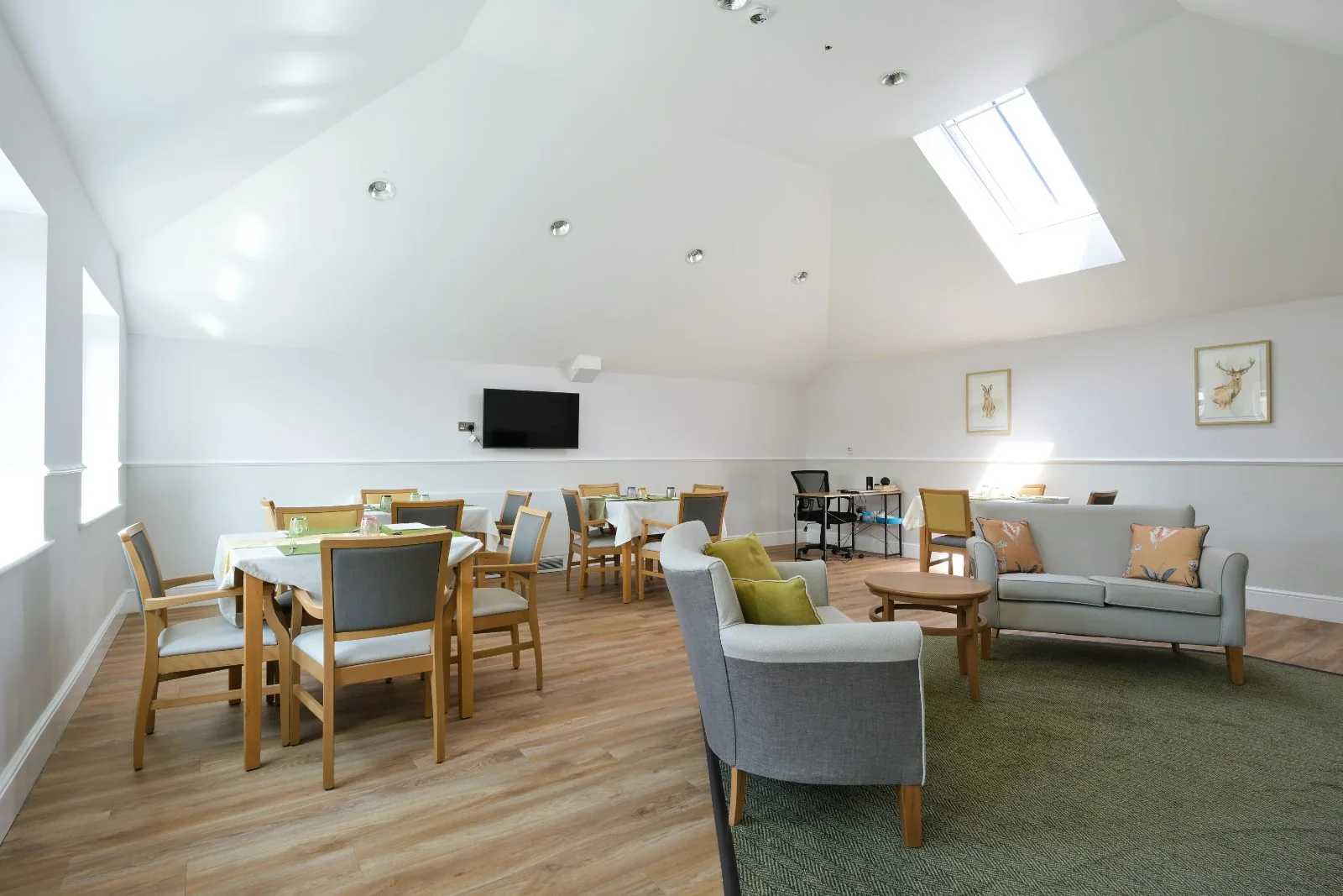 Bright room with dining tables, armchairs, a sofa and a skylight