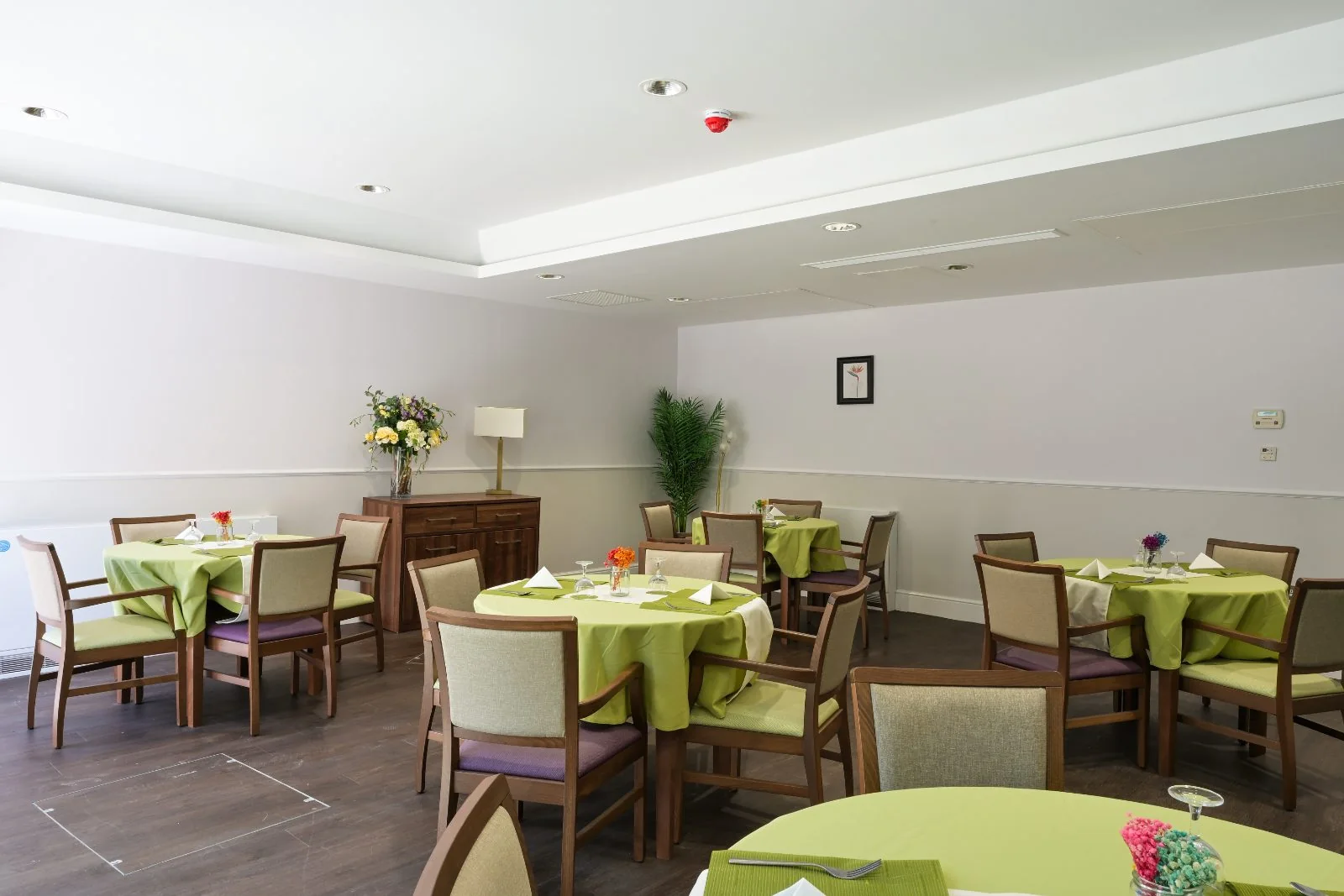 Dining room with round tables, flowers and a sideboard