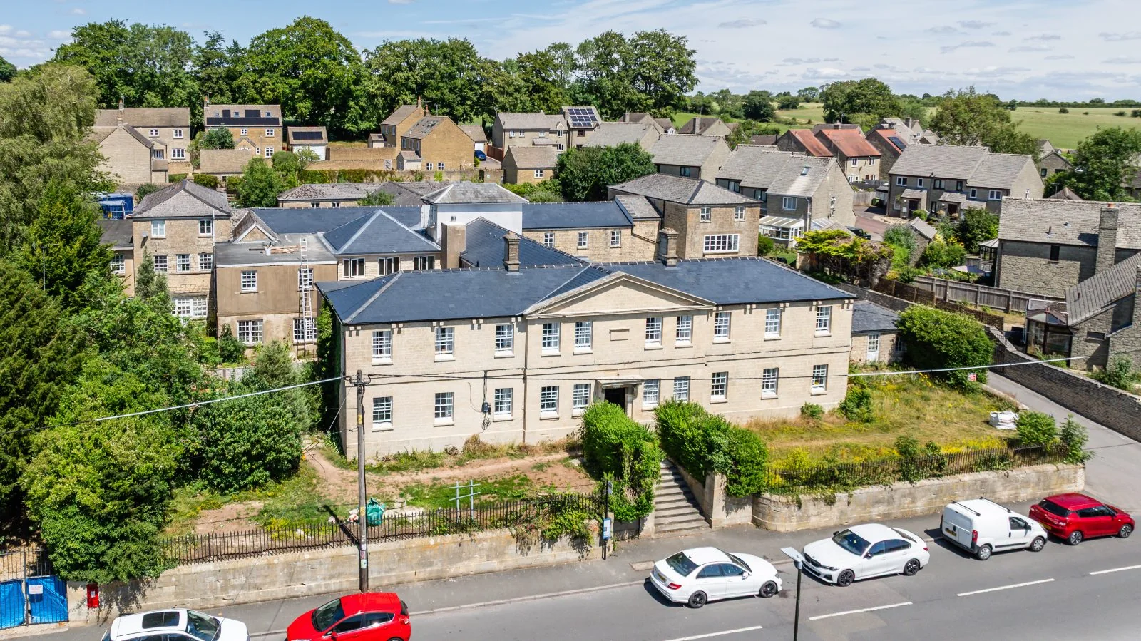 The pedimented Cotswold-stone front of Northleach Court with steps up from the High Street