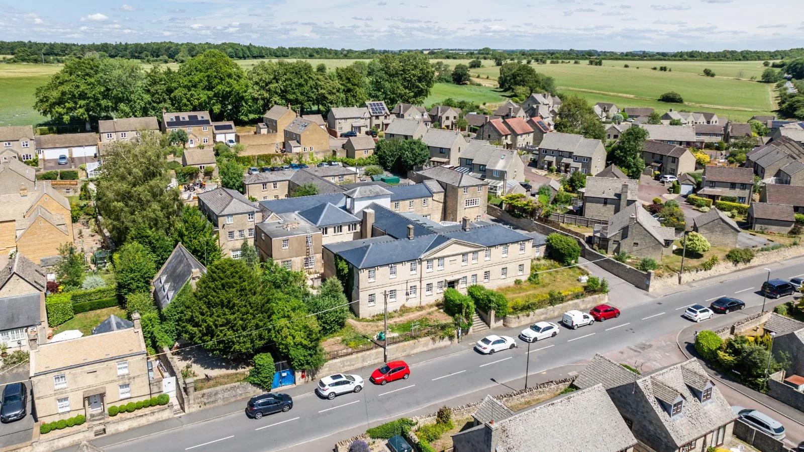Aerial view of the home among stone houses with farmland beyond