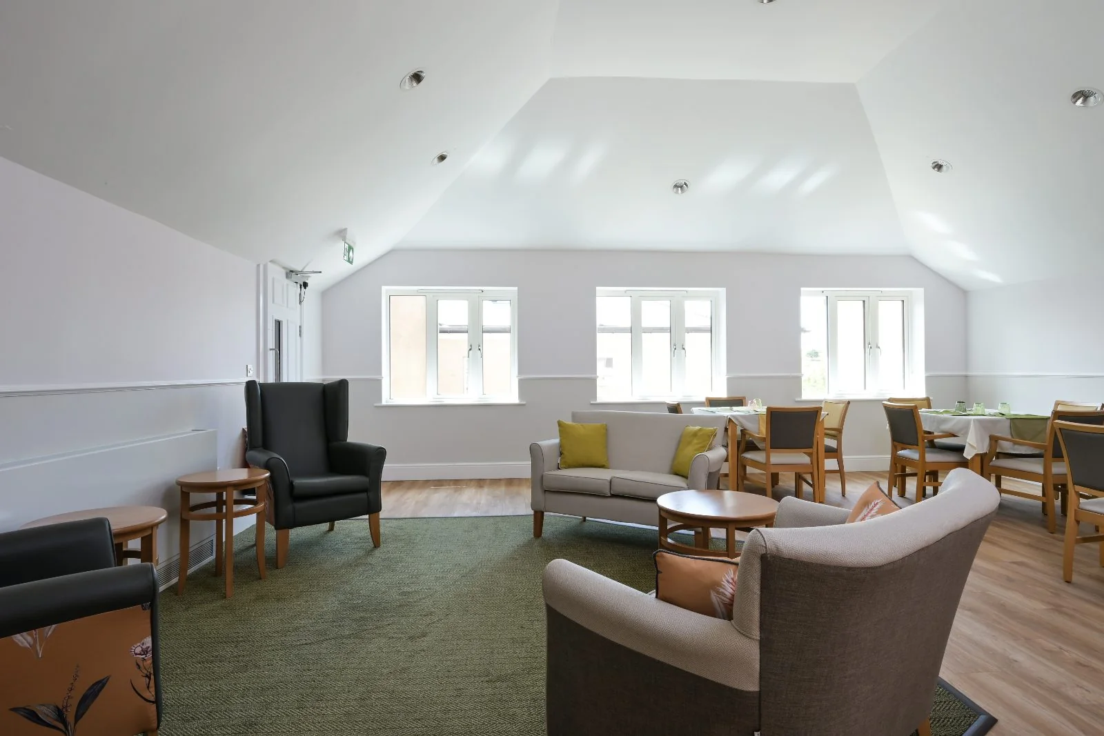 Lounge with wing-back chairs, a sofa and three windows